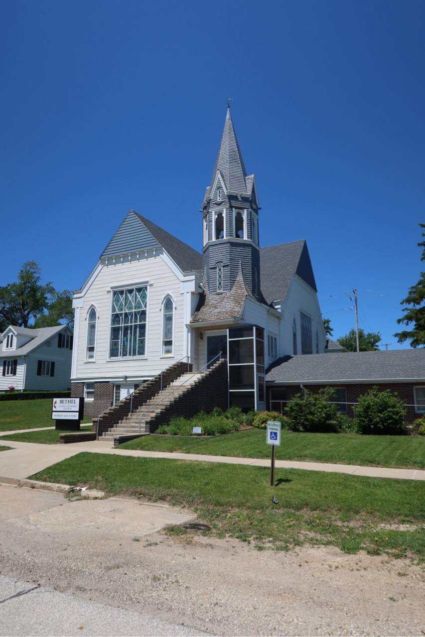A white church with a tall steeple against a blue sky